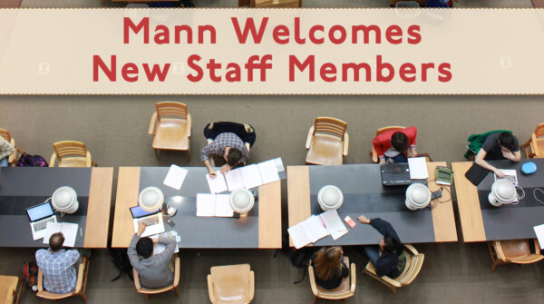 Photo of students studying at large table with text "Mann Welcomes New Staff Members"