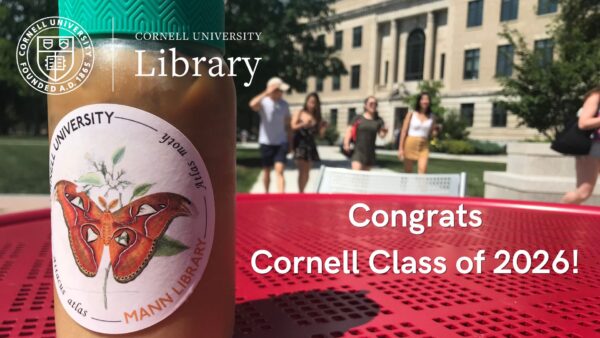 Promotional image celebrating Cornell's Class of 2026. An iced coffee tumbler with a Mann Library moth illustration sticker sits on a red outdoor table in the foreground, with students and a campus building blurred in the background. The Cornell University Library logo appears at the top left, and the text reads: "Congrats Cornell Class of 2026!"