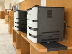 Public CU Print printers on wooden counters in the library